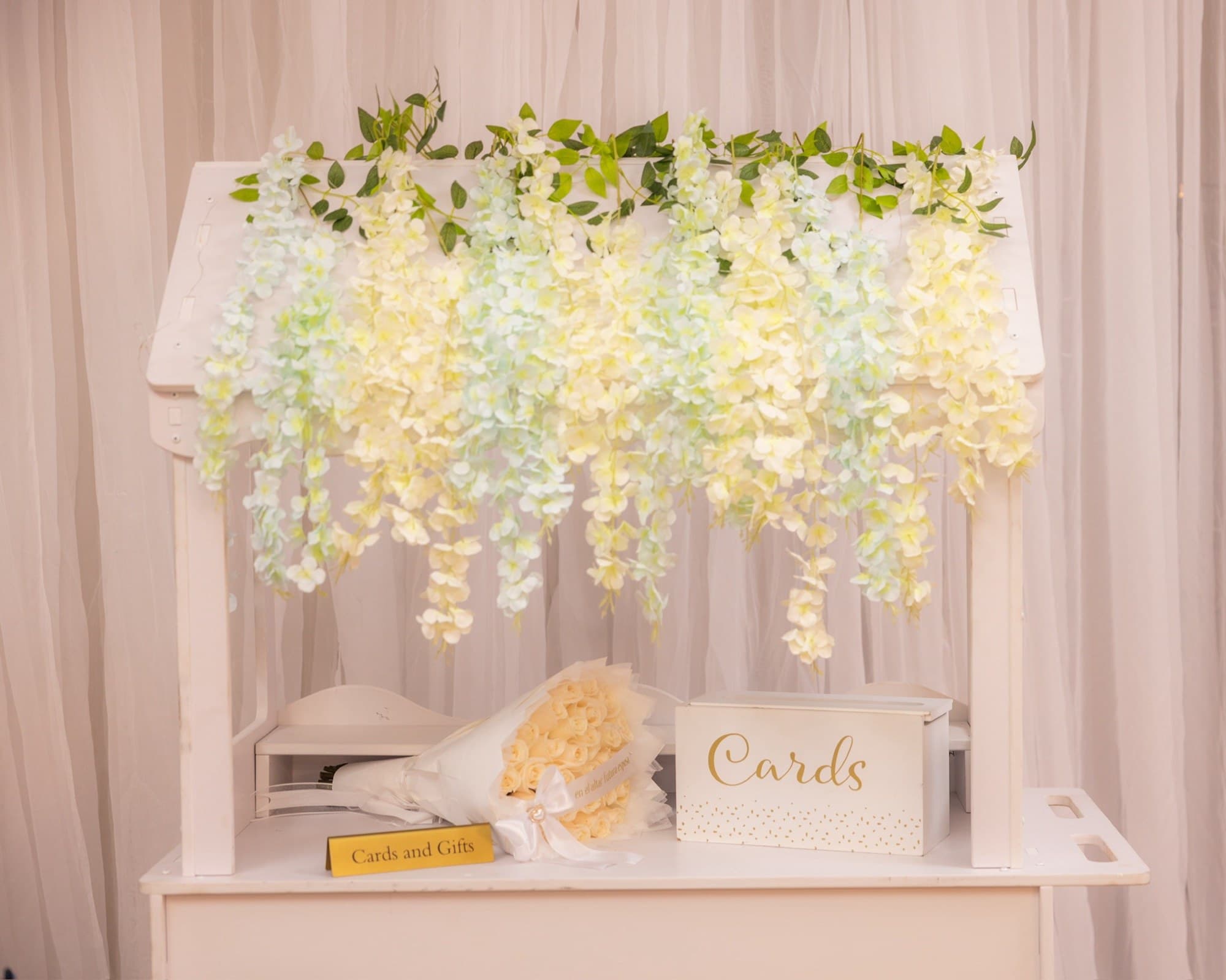 Mesa de tarjetas y regalos con flores colgantes de glicina