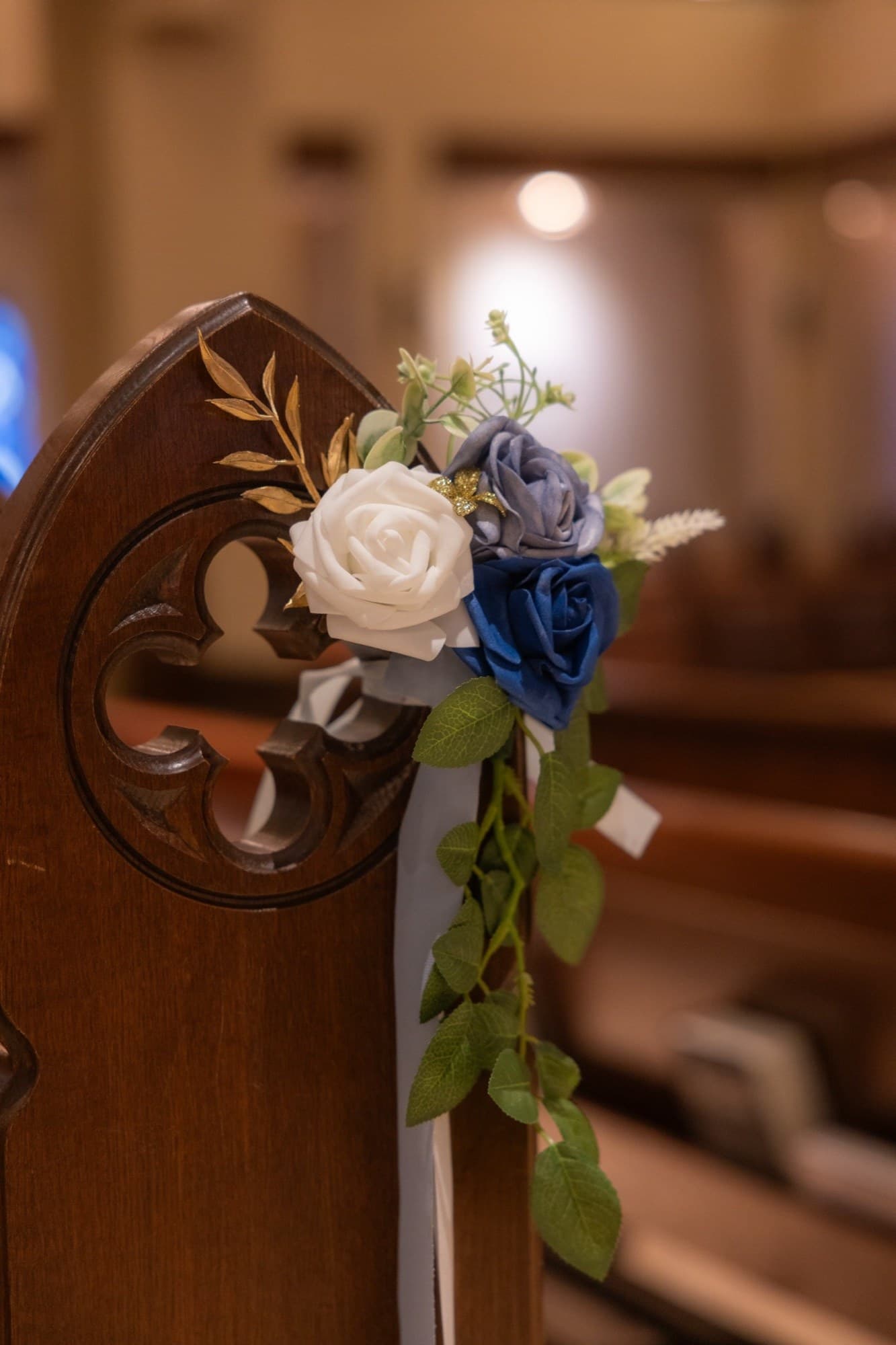 Arreglo de rosas azules, blancas y doradas en una banca de la iglesia