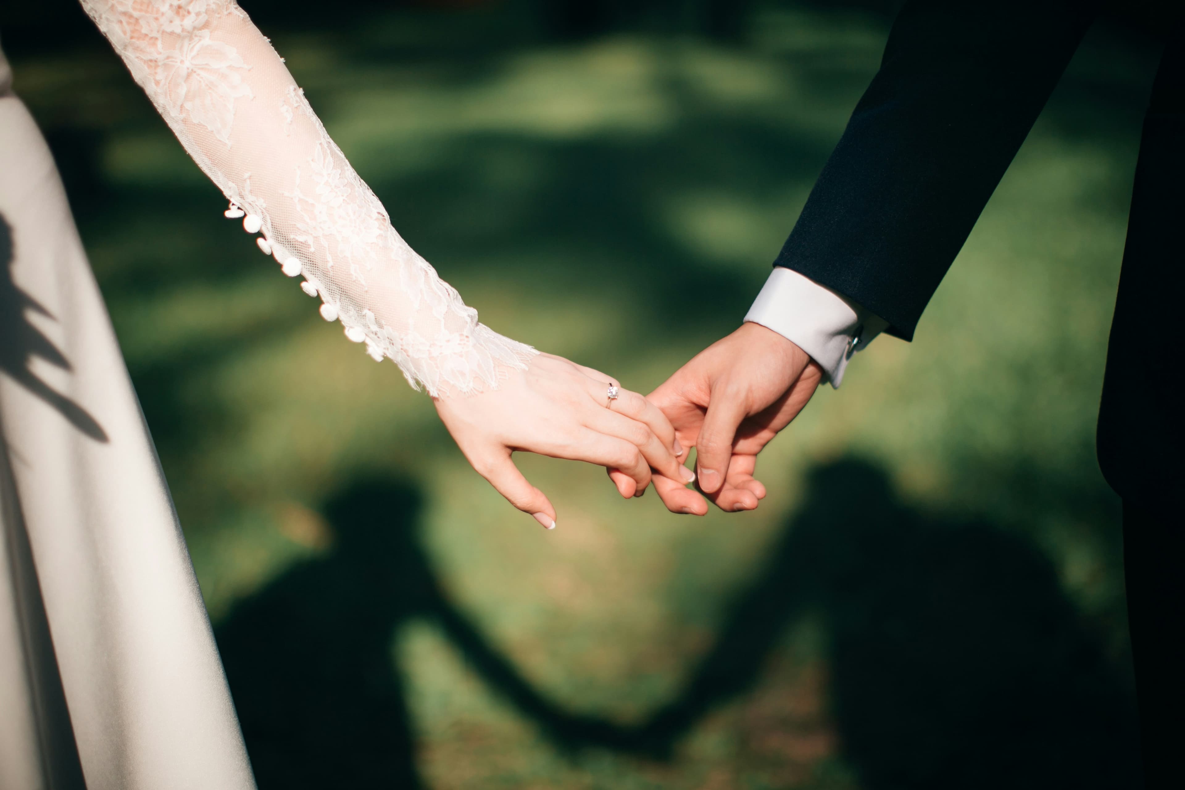 A bride and groom holding hands in soft afternoon light on their wedding day